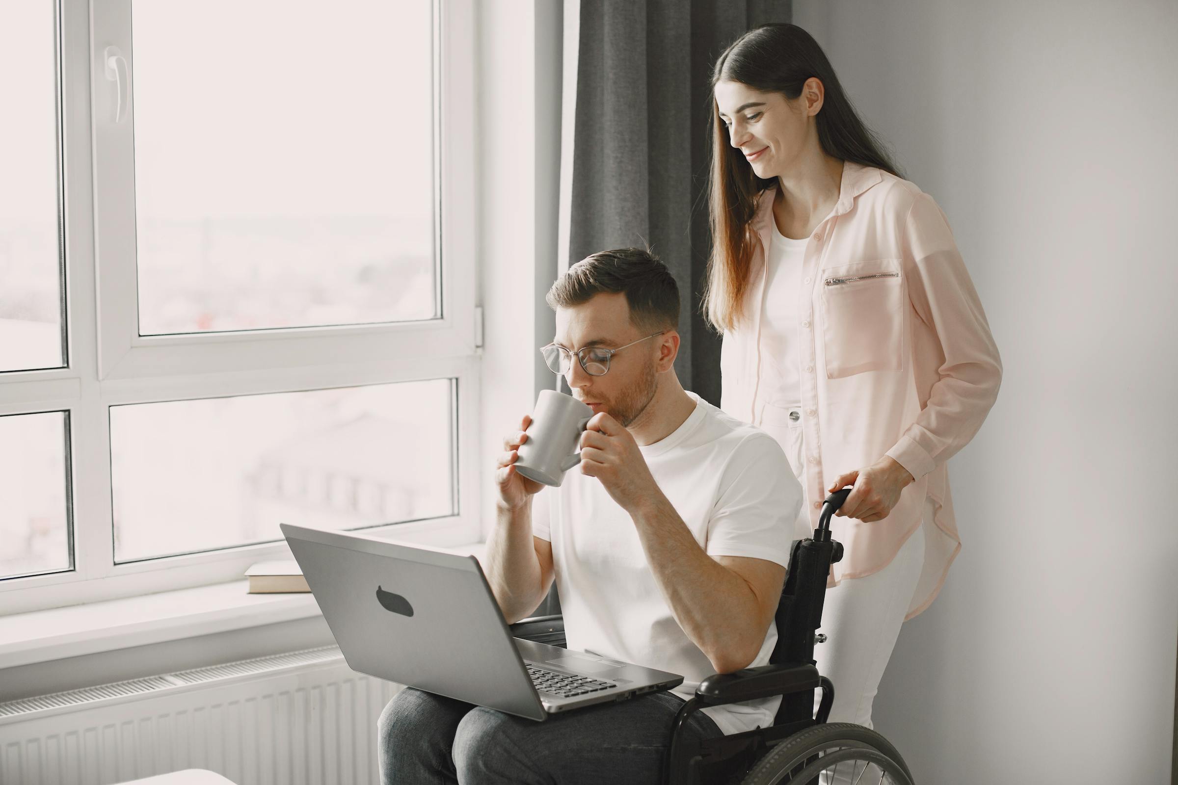 A support worker smiling warmly beside a man enjoying a coffee at home